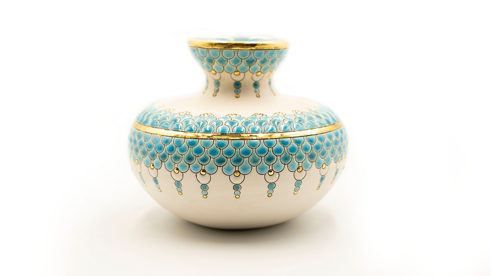 Intricately designed ceramic vase with blue and gold patterns against a plain white background.